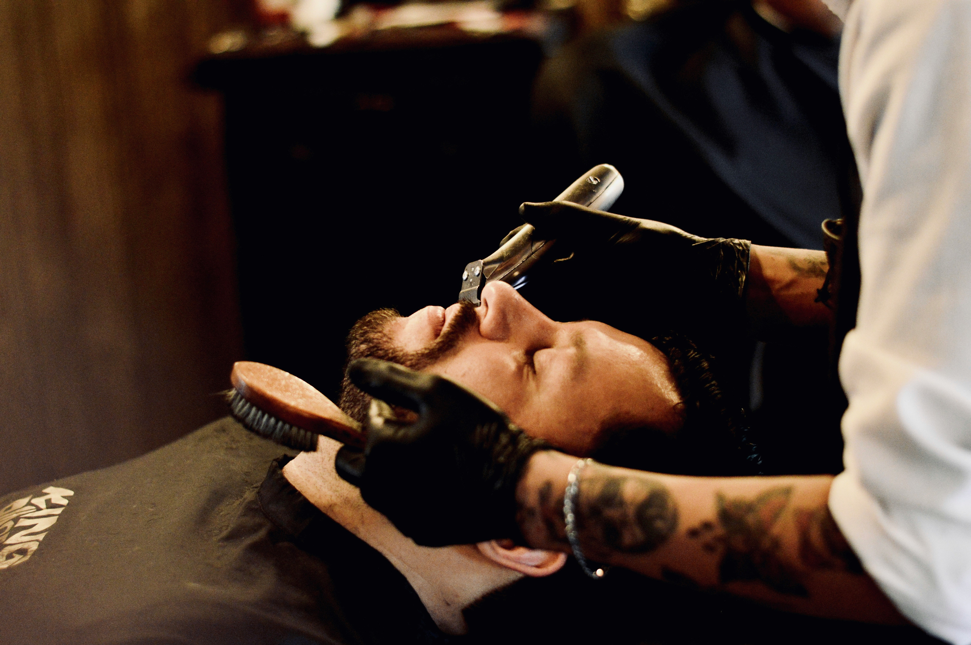 A barber giving a straight-razor shave — the kind of craftsmanship that builds repeat clients.