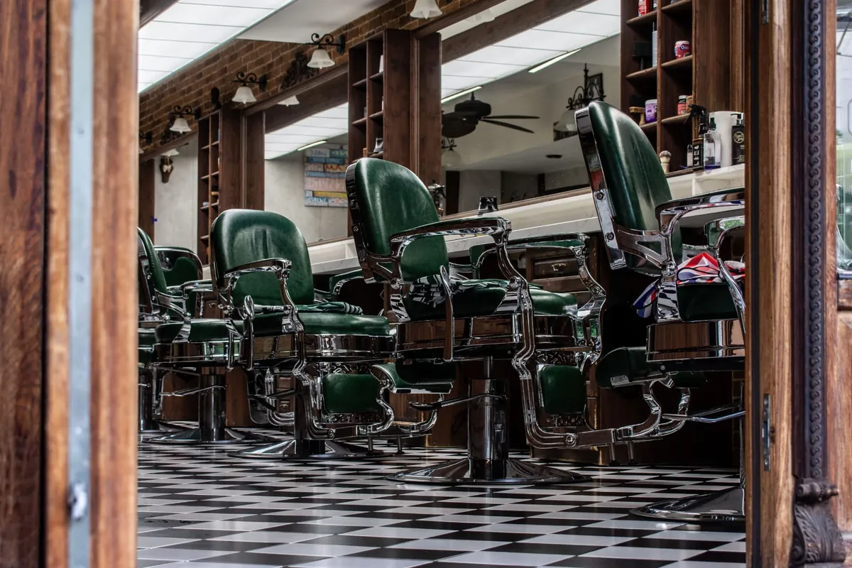 A row of vintage green leather barber chairs on a checkered floor — the kind of space barbers find when searching chair rental near me.