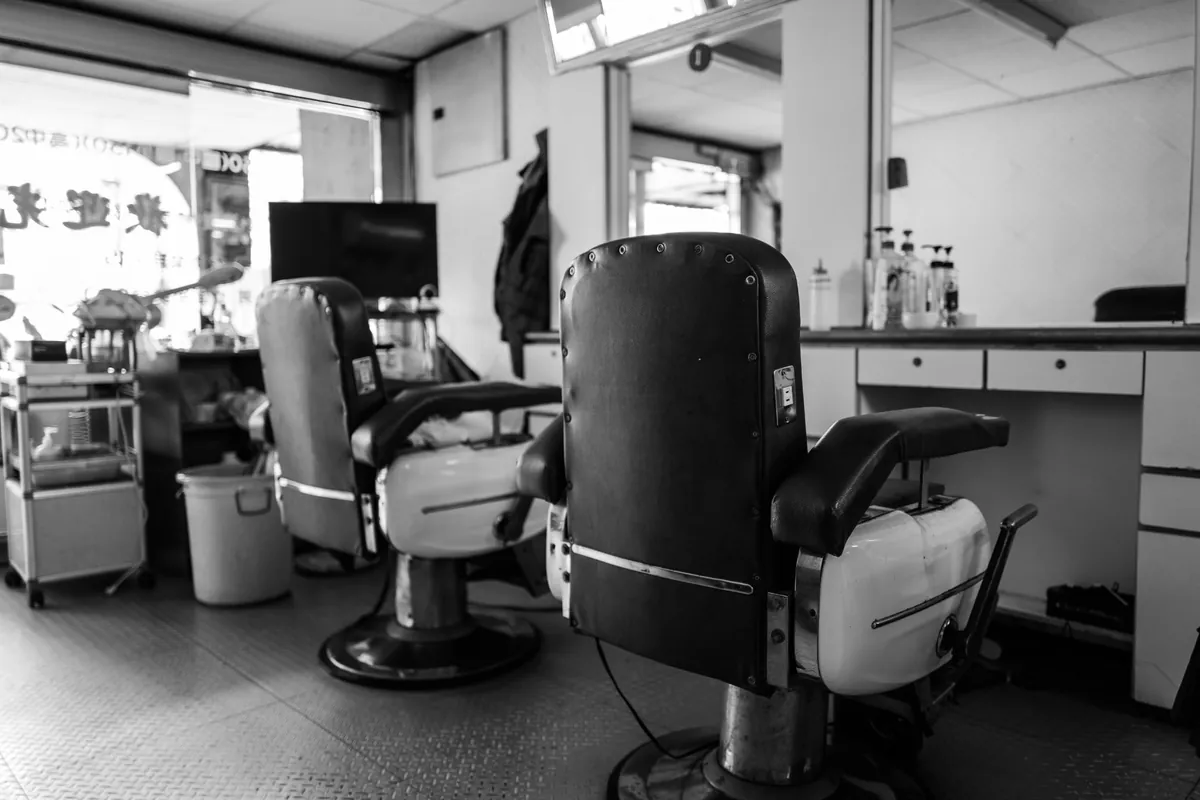 Two empty vintage barber chairs facing mirrors in a quiet shop.